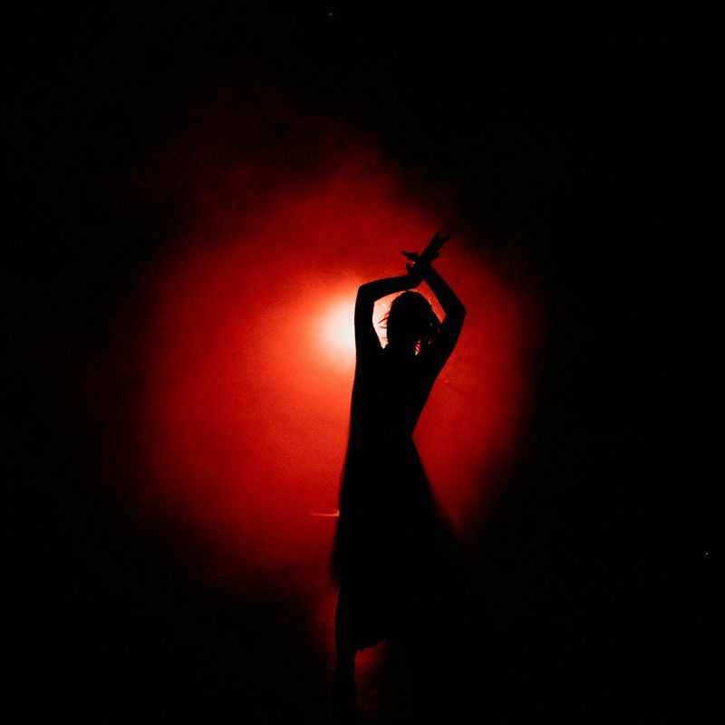 Silhouette of a person in a dynamic, dance-like yoga pose with amber light.